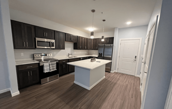 A kitchen with dark brown cabinets and a white island.